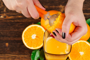 Woman hand squeezes orange juice close up