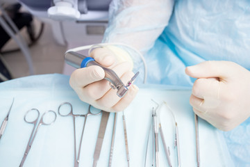 During the operation, the dentist holds implantation tools with a titanium implant