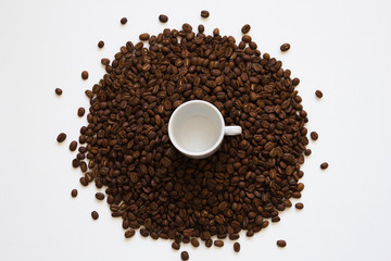white cup on coffee beans on a white background, top view