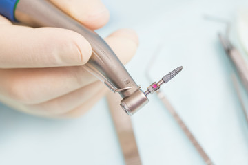 During the operation, the dentist holds implantation tools with a titanium implant
