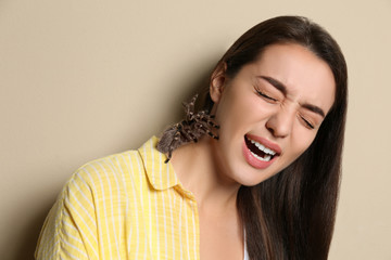 Scared young woman with tarantula on beige background. Arachnophobia (fear of spiders)