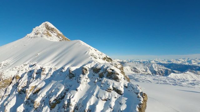 Aerial fpv shot climbing along snow-caped alpine summit ridge towards Oldenhorn summit. Swiss winter alpine scenery. Les Diablerets, Switzerland