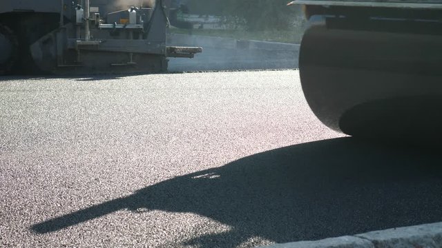 New asphalt road under construction. Roller rolling fresh hot asphalt. Compaction of the pavement in road construction