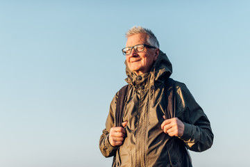 Senior man trail hiking in a mountain forest.