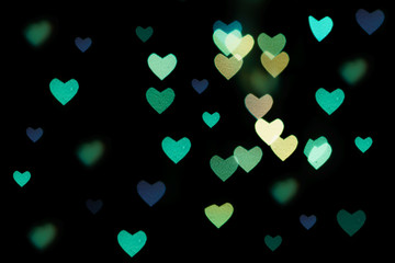 Fototapeta na wymiar Multicolored hearts bokeh of blue color on black background. Texture for holidays