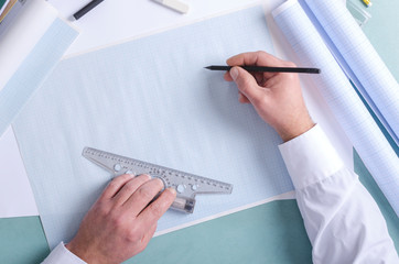 Top view of constuctor`s hands who using t-square and pencil. Draftsman at work, drafting on the...