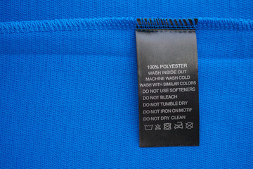 Black laundry care washing instructions clothes label on blue jersey polyester sport shirt