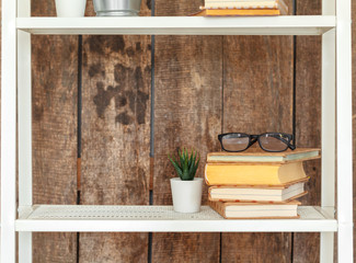 Fototapeta na wymiar Close up of white bookshelf against grunge wooden wall