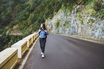 Traveler woman with backpack enjoying and walking on the road in the mountains.