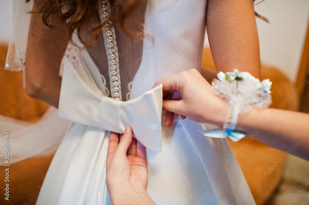 Wall mural morning of the bride preparation. young and handsome bride at wedding day. bridesmaid tie bow.