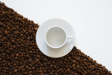 white cup on coffee beans on a white background, top view