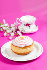 Fresh doughnut on a pink background, flowers and decorations