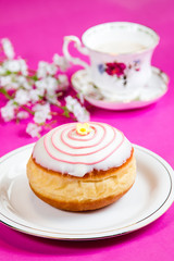 Fresh doughnut on a pink background, flowers and decorations