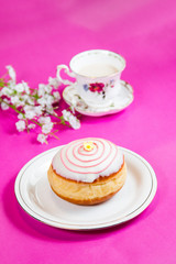Fresh doughnut on a pink background, flowers and decorations