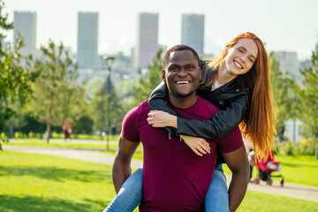 Portrait of young man hugging his girlfriend standing together on a spring summer park on a sunny day