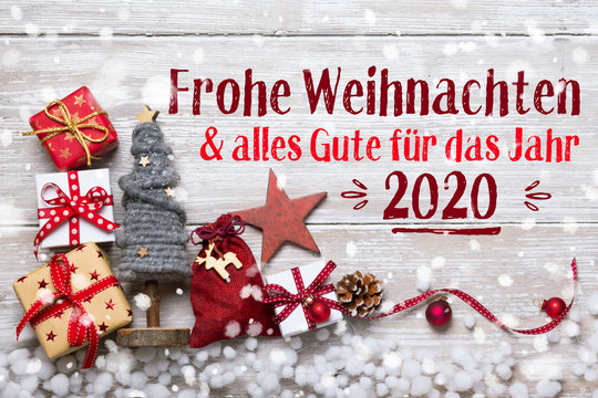 Merry Christmas and Happy New Year 2020 - Christmas Greeting Card 2019, 2020 - German language - Xmas Decoration with gift boxes and ornaments on light rustic wood