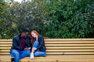 Fototapeta premium Portrait of young man hugging his girlfriend standing together on a spring summer park on a sunny day