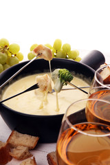 Gourmet Swiss fondue dinner on a winter evening with assorted cheeses on a board alongside a heated...