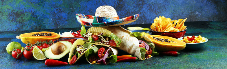 Mexican food, including tacos, guacamole, nachos and pepper on rustic table