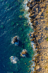 Aerial of ocean waves hitting rocky shore