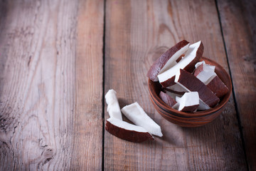 Ceramic bowl with coconut slices on a wooden background.