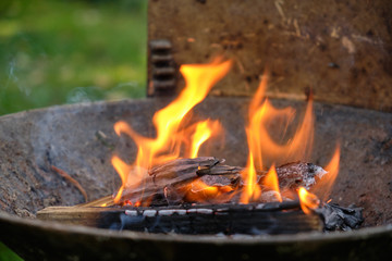 Flames coming out of a heap of cardboard, paper, wood and twigs before in a barbecue used to lighten it up before putting the charcoal in