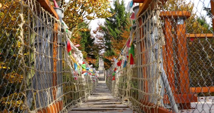 Himalayan sidewalk, deep in nature Skywalk wooden construction of viewpoint hitting by strong wind tree trunks colored flags during sunny autumn day captured in Radhost, Pustevny area 4k 60fps.