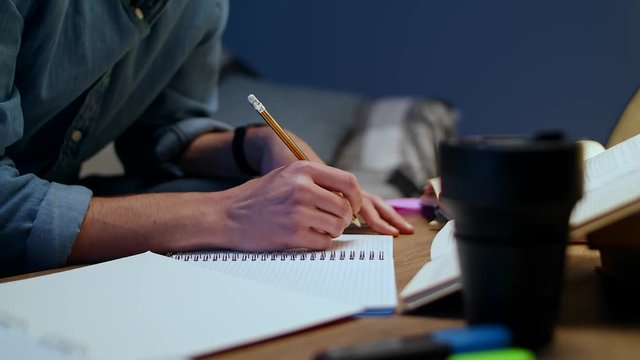 Young man makes notes while studying in the evening