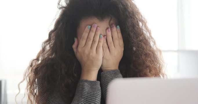 Woman doing a facepalm after receiving negative news on office laptop