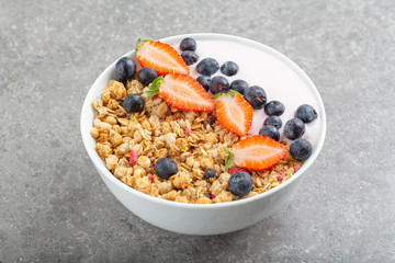 Granola with yogurt fresh strawberries and blueberries on a stone table. Healthy snack. The food for Breakfast. 
