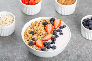 Granola with yogurt fresh strawberries and blueberries on a stone table. Healthy snack. The food for Breakfast. 