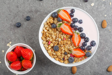Granola with yogurt fresh strawberries and blueberries on a stone table. Healthy snack. The food for Breakfast. Top view.