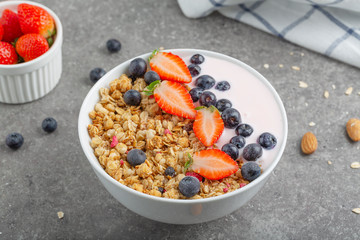 Granola with yogurt fresh strawberries and blueberries on a stone table. Healthy snack. The food for Breakfast. 