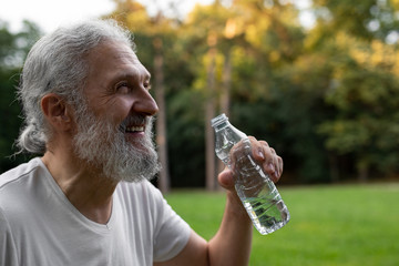 Handsome senior man is drinking water in the nature