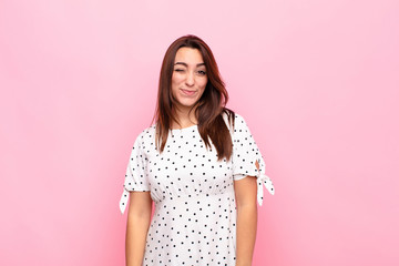 young pretty woman looking happy and friendly, smiling and winking an eye at you with a positive...