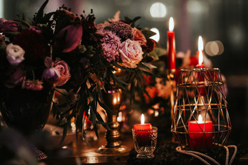 Beautiful, decorated table with flower decorations and red candles. Christmas evening or wedding party decoration.