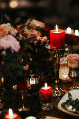 Beautiful, decorated table with flower decorations and red candles. Christmas evening or wedding party decoration.