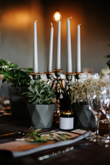 Table decoration with burning candles, white flowers. Romantic Christmas or party atmosphere.