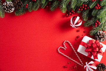 Christmas background concept. Top view of Christmas gift box red balls with spruce branches, pine cones, red berries star and bell on red background.