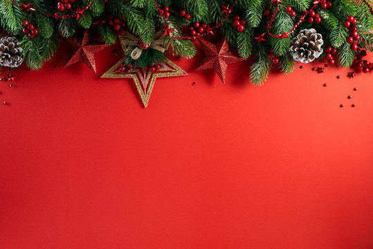 Christmas background concept. Top view of Christmas gift box red balls with spruce branches, pine cones, red berries star and bell on red background.