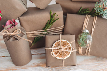 Pile of presents and gifts wrapped in craft paper with decoration on white wooden background. Flat lay, close up.