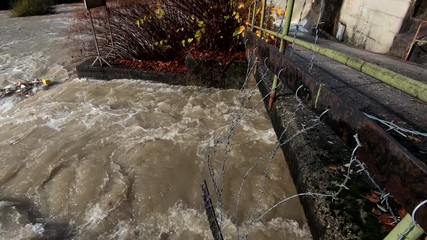 Slow motion left truck moving by small concrete bridge and dirt flooded water flowing in narrow canal - Powered by Adobe