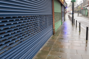 Fototapeta na wymiar High Street Shops closing down with shutters closed, decline in shopping in Wales, United Kingdom