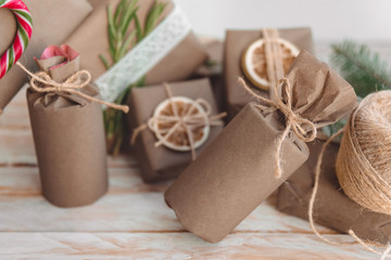 Pile of presents and gifts wrapped in craft paper with decoration on white wooden background. Flat lay, close up.