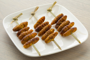 Dish with crispy silkworms on a stick