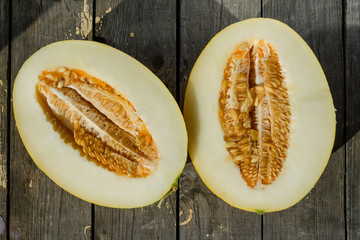 melon cut into two halves on a wooden cutting board. Top view.