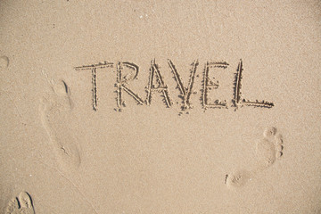 Word TRAVEL drawn on the sand of sandy beach