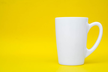 White ceramic cup on yellow background. Space for text