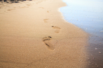 Traces of feet on the beach yellow sand.