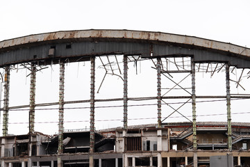Demolition of the arena. Old metal frame of the building, destroyed walls.